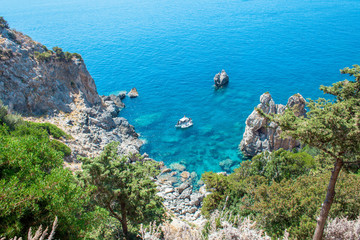 Fototapeta premium Beautiful summertime panoramic seascape. View of the cliff into the crystal clear azure sea bay and distant islands. Unique secluded beach. Agios Stefanos cape. Afionas. Corfu. Greece.