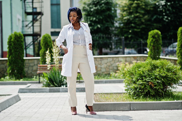 Stylish african american doctor with stethoscope and lab coat posed at backyard of hospital.