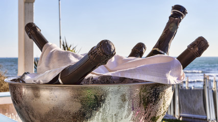 Bottles of chilled champagne inside a metallic container full of ice - selective focus