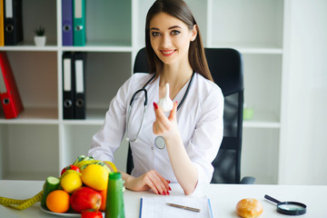 Health. The Doctor Dietitian Holds in the Hands of Garlic. Healthy Nutrition. Fresh Vegetables and Fruits on the Table. Happy Doctor in the Ligh Room.