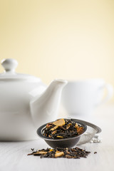infuser with black tea on table with teapot