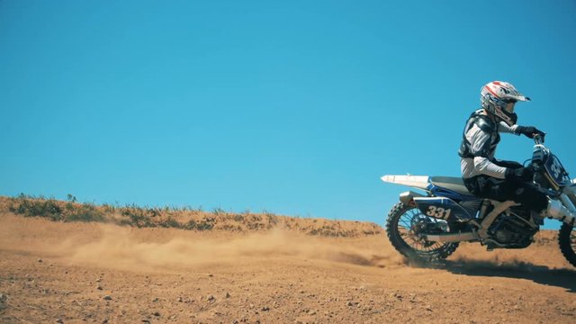 Motorider is driving his autobike through dusty terrain