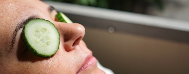 Young woman in a beauty spa with cucumber mask