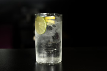 Close up of glass of a freshly prepared gin and tonic with lime slices and twist of lemon, isolated.