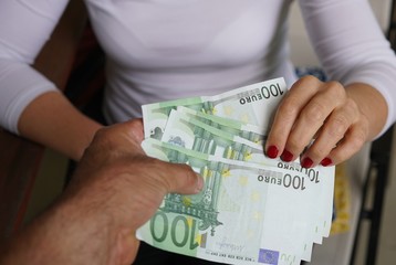 Woman receiving cash money from a man. Cropped image