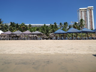 Scenic white hotel and umbrellas on sandy beach at bay of Acapulco city landscape in Mexico at...