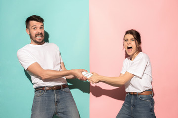 young couple watching tv and fighting to get the remote control