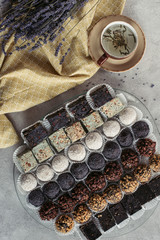 flat lay with cup of herbal tea, sweet desserts and lavender on tablecloth on grey tabletop
