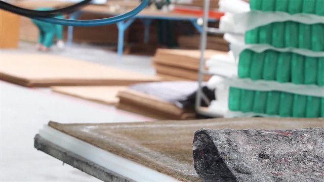 Factory on assembly of orthopedic mattresses, production of mattresses, gluing foam rubber close-up, the worker applies glue on the mattress