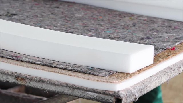 Factory on assembly of orthopedic mattresses, production of mattresses, gluing foam rubber close-up, the worker applies glue on the mattress