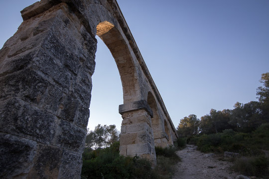 Ancient viaduct bridge from the bottom view in the setting sun