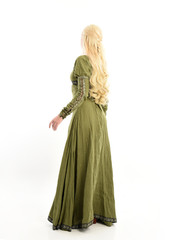 full length portrait of blonde girl wearing green medieval gown, standing pose facing away from camera. isolated on white studio background.