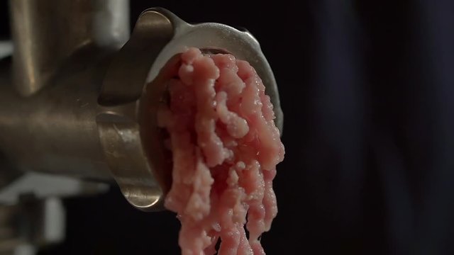 Close up shot of a food grinder grinding raw meat in the kitchen. Working food grinder shaking while grinding meat. Pushing through.