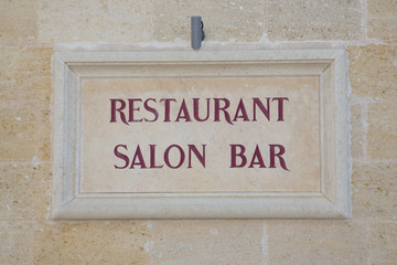 old sign on wall of the restaurant bar in France on an old stone wall of the country