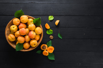 Sweet ripe apricots on black wooden background. Copy space