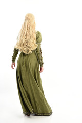 full length portrait of blonde girl wearing green medieval gown, standing pose facing away from...