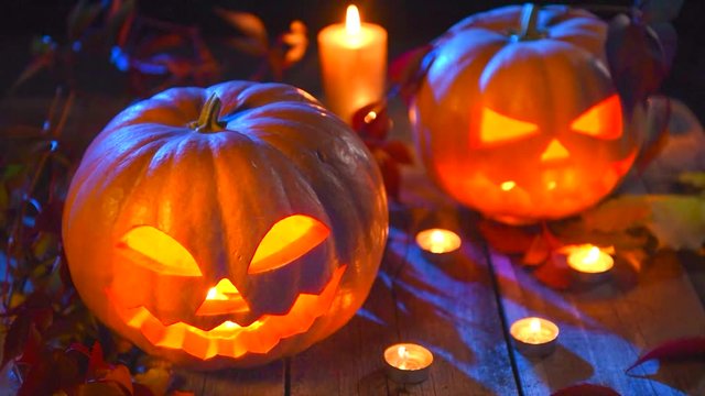 Halloween pumpkin head jack lantern with burning candles over wooden background. 3840X2160 4K UHD video footage