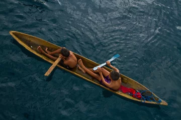 Crédence de cuisine en verre imprimé Indonésie The fisherman boys play on the small traditional paddle boat