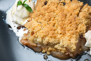 close up of tasty apple crumble dessert with cream