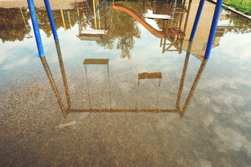 Empty swings on flooded childrens playground