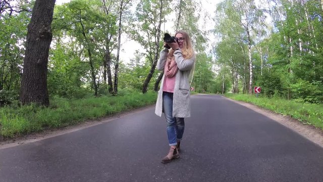 the girl takes pictures on the forest road.