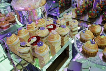 Set of cupcakes around a wedding table. A cupcake is a small cake designed to serve one person and uses ingredients as butter, sugar, eggs, and flour, as well as raisins, nuts, or chocolate chips.