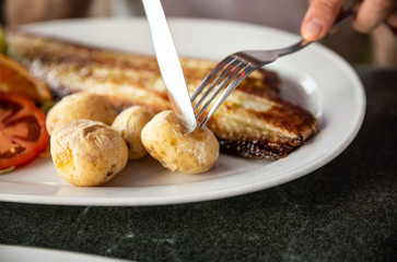 Close up of tasty fried fish and sea fruits with potato and sauce from tomato and chili re paper. Delicious restaurant food near ocean in Spain, Canarias island. Traditional Canarias dish.