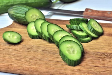 Sliced fresh cucumber on a wooden cutting board.