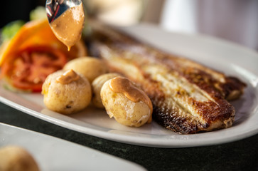 Close up of tasty fried fish and sea fruits with potato and sauce from tomato and chili re paper....