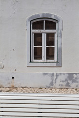 White bench, cobblestones and wall with a window