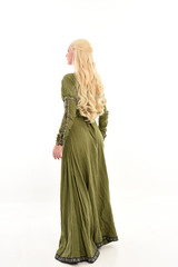 full length portrait of blonde girl wearing green medieval gown, standing pose facing away from camera. isolated on white studio background.