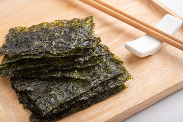 Crispy dried seaweed on wooden plate. © penguiiin