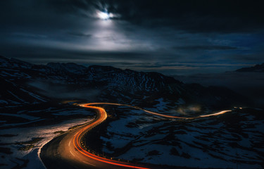 The winding mountain High Alpine Road Pass at night with light tracks from cars, Grossglockner...