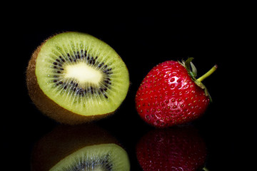 Ripe strawberry with kiwi fruit and reflection on a black background