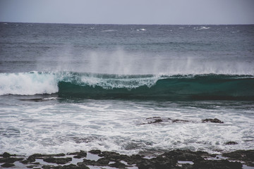 typical windy day in gran canaria, canary islands, spain. ideal for surfing, bigger waves in the sea, turquoise blue water in the ocean