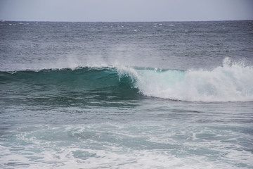 typical windy day in gran canaria, canary islands, spain. ideal for surfing, bigger waves in the sea, turquoise blue water in the ocean