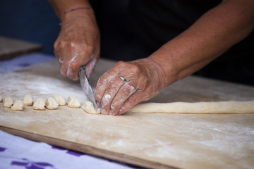 Fototapeta na wymiar The hands of an elderly woman cut the dough into small pieces. Making Donuts