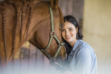 Portrait of smiling woman with a horse on a farm