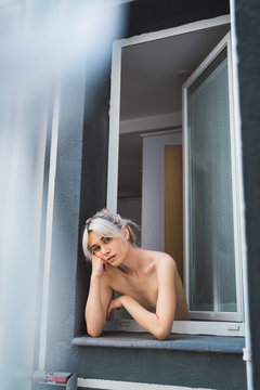 Naked woman looking out window