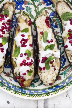 Filled aubergines with couscous, yogurt sauce, mint and pomegranate seeds