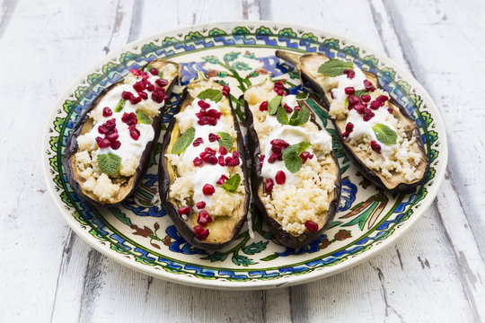 Filled aubergines with couscous, yogurt sauce, mint and pomegranate seeds