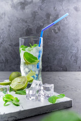 Mojito in glasses, next to lime and mint on the cutting Board. Copy space.