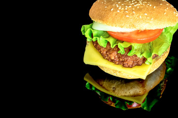 Big fat hamburger with fresh vegetables with reflection isolated on black background. Bright view photo. 