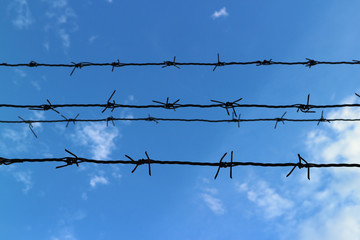 Silhouette of the barbed wire with blue sky and clouds background