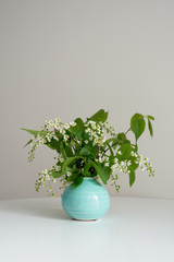 Branch of blossoming bird cherry stands in a round vase