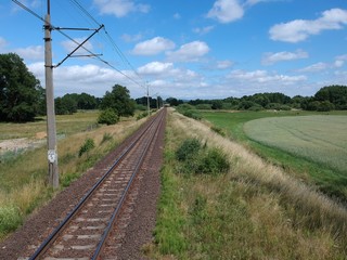 Fototapeta na wymiar Electric railroad in a green natural environment, meadows, trees, grass, aerial view