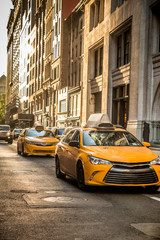 Street view in New York City in midtown Manhattan with yellow taxi cabs and buildings.