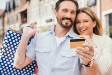 couple hugging and holding shopping bags with credit card on foreground
