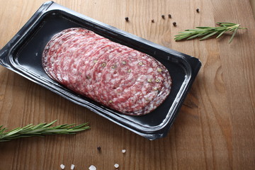 sausage sliced in a package on a wooden background