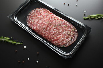 sausage sliced in a package on a dark background